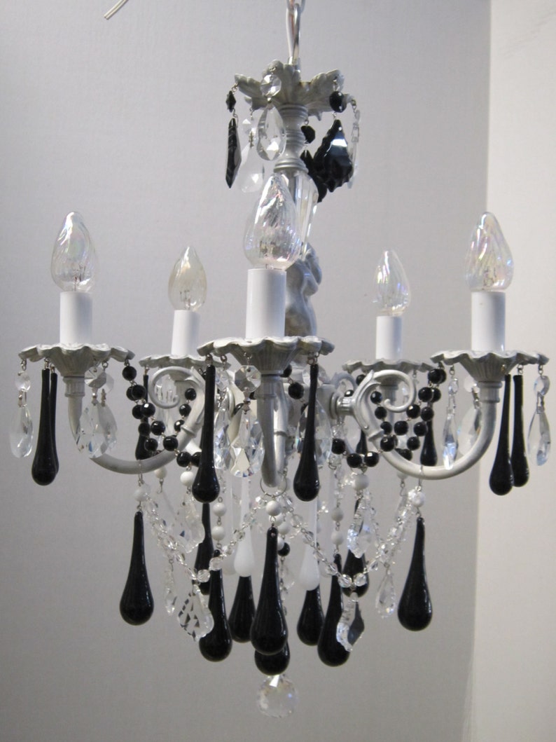 May include: A silver chandelier with black and clear crystal drops. The chandelier has five light bulbs and a decorative top.
