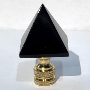 Puede incluir: Fina de lámpara de pirámide negra con base de metal dorado.