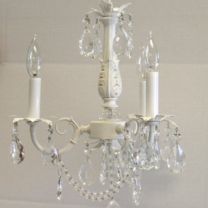 May include: White chandelier with crystal drops and candle-style light bulbs.