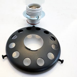 May include: Black metal lamp socket with a round, open-top design and multiple holes. The socket has two screws on the side. A white ceramic light bulb socket is also shown.