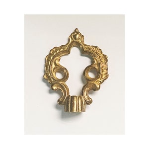 May include: A gold-toned metal decorative finial with a detailed ornate design. The finial has a round base and a pointed top.