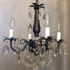 May include: A black chandelier with crystal drops and candle-style light bulbs.