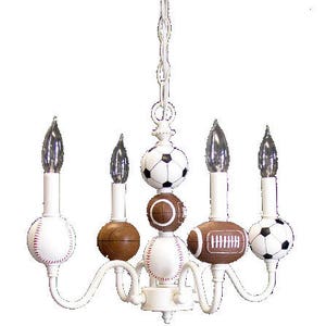 May include: White chandelier with five light bulbs and sports ball-shaped shades. The shades are decorated with baseball, football, and soccer ball designs.
