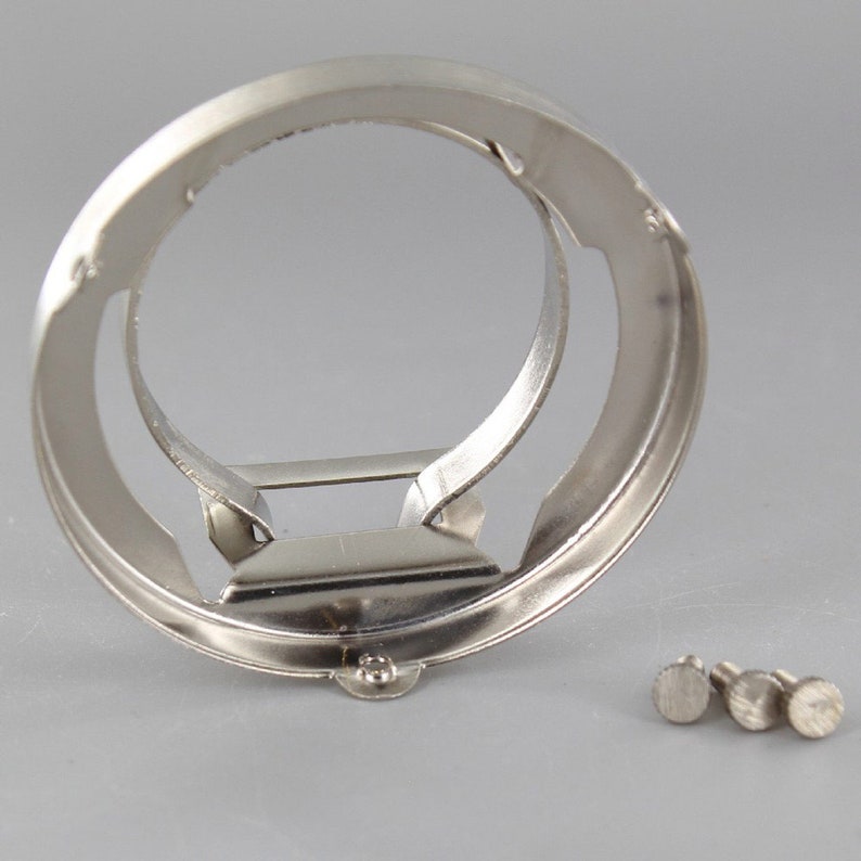 Puede incluir: Un anillo de metal plateado con un anillo m&aacute;s peque&ntilde;o en su interior. El anillo est&aacute; dise&ntilde;ado para sujetar una bombilla. Se incluyen tres peque&ntilde;os tornillos plateados.