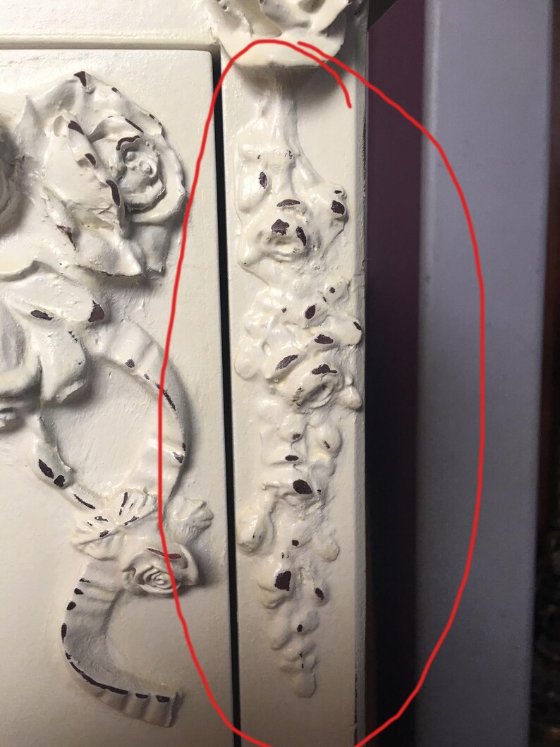 May include: White painted wooden cabinet with ornate floral carvings. The cabinet has a distressed finish and a decorative floral design on the side.