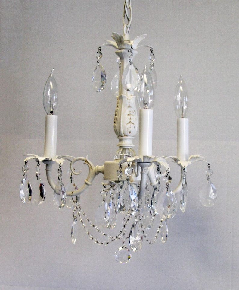 May include: White chandelier with crystal drops and three candle-style light bulbs.