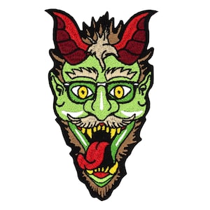Könnte beinhalten: Grünes Monstergesicht mit roten Hörnern, einem braunen Bart und einem weit geöffneten Mund mit einer roten Zunge. Das Monster trägt eine grüne Brille.