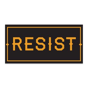 May include: A black rectangular sign with a gold border and the word "RESIST" in gold letters.