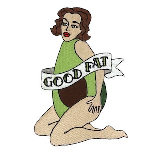 Könnte beinhalten: Ein gestickter Aufnäher mit einer Comic-Frau mit braunen Haaren, die ein grünes Avocado-Kostüm trägt. Die Frau sitzt mit gekreuzten Beinen und hält den Avocado-Kern. Ein weißes Banner mit dem Text "GOOD FAT" ist um die Avocado gewickelt.