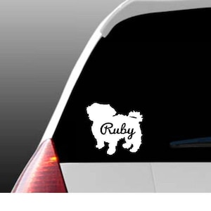 May include: White vinyl car decal of a dog silhouette with the name "Ruby" written inside the silhouette.