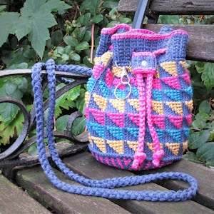May include: A blue, pink, and yellow crocheted drawstring bag with a long blue strap. The bag is made of a textured yarn and has a geometric pattern.
