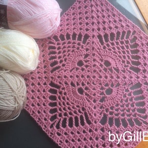 May include: A square, dusty rose crochet doily with an openwork floral design, next to three balls of yarn in pink, cream, and beige. The text "by GillBux" is in the bottom right corner.
