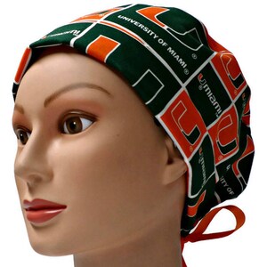 May include: Green and orange scrub hat with the University of Miami logo. The hat has a tie on the back.