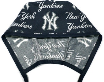 May include: A navy blue surgical cap with a white New York Yankees logo and text pattern. The cap has two long ties.