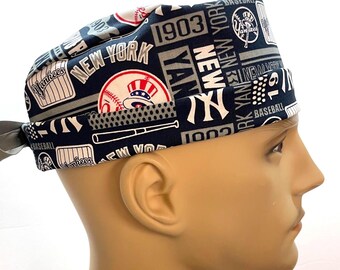 May include: A navy blue and white baseball cap featuring the text "New York Yankees" and baseball-themed graphics. The cap includes the team logo, the year 1903, and the word "Baseball". The cap is designed to be worn on the head.