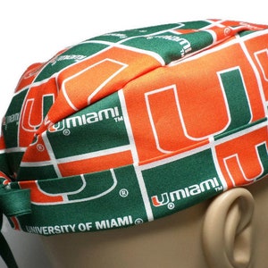 Puede incluir:  gorro de quir&oacute;fano verde y naranja con el logotipo de la Universidad de Miami y el texto "University of Miami".