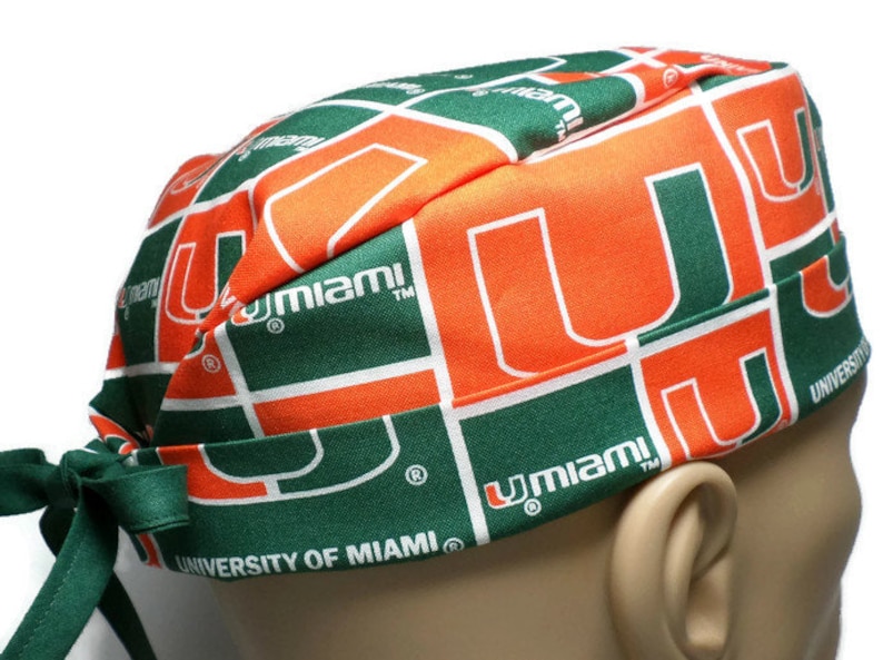 Puede incluir:  gorro de quir&oacute;fano verde y naranja con el logotipo de la Universidad de Miami y el texto "University of Miami".