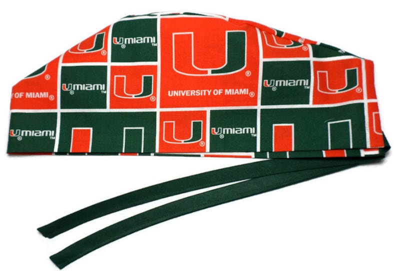 Puede incluir:  gorro de quir&oacute;fano verde y naranja con un patr&oacute;n repetido del logotipo de la Universidad de Miami y las palabras "U Miami".