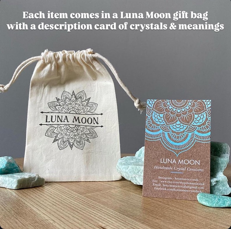 May include: A white cotton drawstring bag with the text "LUNA MOON" printed on it. The bag is sitting on a wooden surface next to a brown card with a blue mandala design and the text "LUNA MOON Handmade Crystal Creations".