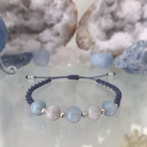 May include: A blue and white beaded bracelet with silver beads and a dark blue cord.