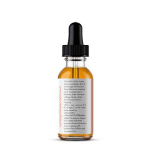 Op de afbeelding: Een doorzichtige glazen fles met een zwarte druppelaar bovenop, gevuld met een licht amberkleurige vloeistof. De fles is gelabeld met de tekst "Great for all skin types. Enzymes exfoliate skin & encourage cell turnover. Very effective in treating acne. Increases skin's firmness, helps maintain collagen levels, which prevents premature sagging. Rich in zinc, vitamins A & E, omega 3- and 6- fatty acids as well as antioxidants. Powerful DHT Blockers inhibit the enzyme known as 5-alpha reductase enzyme. Prevents hair loss, encourages growth, protects hair follicles and increases shine." en de website "www.cedarcreekessentials.net".