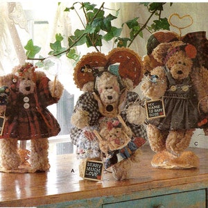 May include: A Simplicity Crafts pattern for making three teddy bear dolls. The pattern includes instructions for making a teddy bear doll with a red plaid dress, a teddy bear doll with a blue and white patchwork dress, and a teddy bear doll with a blue and white gingham dress. The pattern also includes instructions for making a small basket, a small hat, and a small sign. The pattern is titled "Dream Babies" and is for "Stitches".