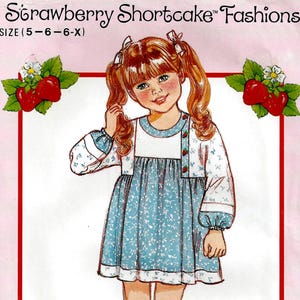 May include: A vintage Butterick sewing pattern featuring a drawing of a young girl in a blue floral dress and white cardigan. The pattern is labeled "Strawberry Shortcake Fashions" and includes the size range (5-6-6-X). The image has a pink border with strawberry illustrations.