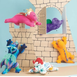 May include: Simplicity pattern S9876 featuring plush dragon toys in various colors, including pink, purple, blue, and orange. The image includes a castle backdrop and the text "U.S. ONE SIZE" and "Designed and printed in USA."