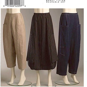 May include: Vogue Patterns V8499 Marcy Tilton sewing pattern for pants and a skirt. The image displays three garments: tan cropped trousers, a black and white striped skirt, and dark blue trousers with visible white stitching and side pockets.