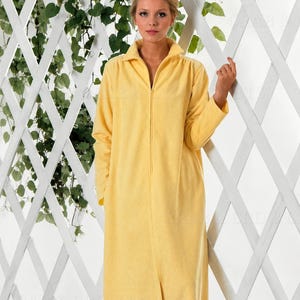 May include: A floor-length, bright yellow robe featuring a full-length front zipper closure, a structured collar, and long sleeves. The garment is crafted from a soft, textured fabric and extends to the floor, providing full coverage.