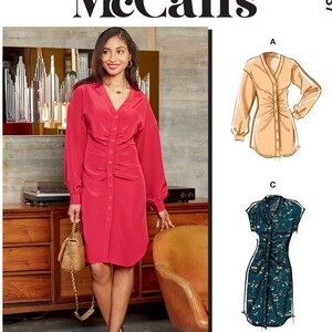 May include: A sewing pattern featuring three different styles of dresses. The first dress is a red button-down dress with long sleeves. The second dress is a beige button-down dress with long sleeves. The third dress is a short-sleeved dress with a floral print. The pattern includes simple instructions. "Designed and printed in USA" is printed on the pattern.
