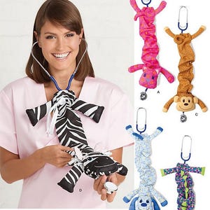 May include: Simplicity pattern 1730 featuring various stuffed animal stethoscope covers. The pattern includes a zebra, a pink hippo, a brown monkey, a blue dog, and a green alligator. The pattern is one size and includes the Simplicity logo.