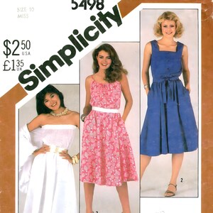 May include: A sewing pattern for three different dresses. The pattern is for size 10 and is called Simplicity 5498. The dresses are a white skirt with a white top, a pink floral skirt with a white top, and a blue skirt with a blue top. The pattern is for a miss petite.