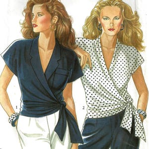 May include: A New Look 6081 sewing pattern envelope featuring illustrations of two wrap-style tops. One is a solid navy blue short-sleeve top with a chest pocket, and the other is a white top with black polka dots, both tied at the waist.