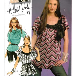 May include: McCall's M5708 sewing pattern featuring a top with a black bow and a pink and black chevron design. The pattern includes a photo of Hilary Duff and illustrations of the top in different styles. Size DD (12-14-16-18).