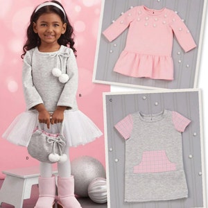 May include: Simplicity sewing pattern number 8805 for girls' dresses in sizes 1/2-4. The pattern includes three different styles: a grey dress with a tulle skirt and pom-poms, a pink dress with pom-poms, and a grey dress with a pink plaid pocket.