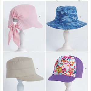 May include: Simplicity pattern S9509 featuring four different hat designs. Includes a pink cap with a bow, a blue camouflage bucket hat, a tan military-style cap, and a purple baseball cap with a floral print.