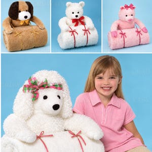 May include: A collection of plush animal blankets featuring a brown dog, a white bear, a pink pig, and a white poodle. Each animal is attached to a rolled, textured blanket secured with ribbons. The poodle version includes a green and pink bow.