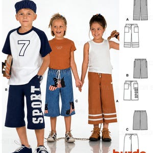 May include: A sewing pattern for children's shorts featuring three variations: navy blue shorts with white 'SPORT' text, blue denim shorts with star-patterned patches, and brown shorts with white stripes. Includes technical line drawings and the Burda logo.