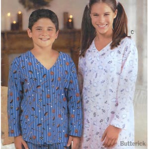 May include: Two people wearing matching pajamas. One person is wearing a blue pajama top and bottom set with a pattern of basketballs, golf clubs, and stripes. The other person is wearing a white nightgown with a pattern of clouds and cars.