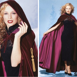 May include: A long, burgundy velvet cape with a hood and a gold tassel. The cape is worn over a black dress with a high neckline.