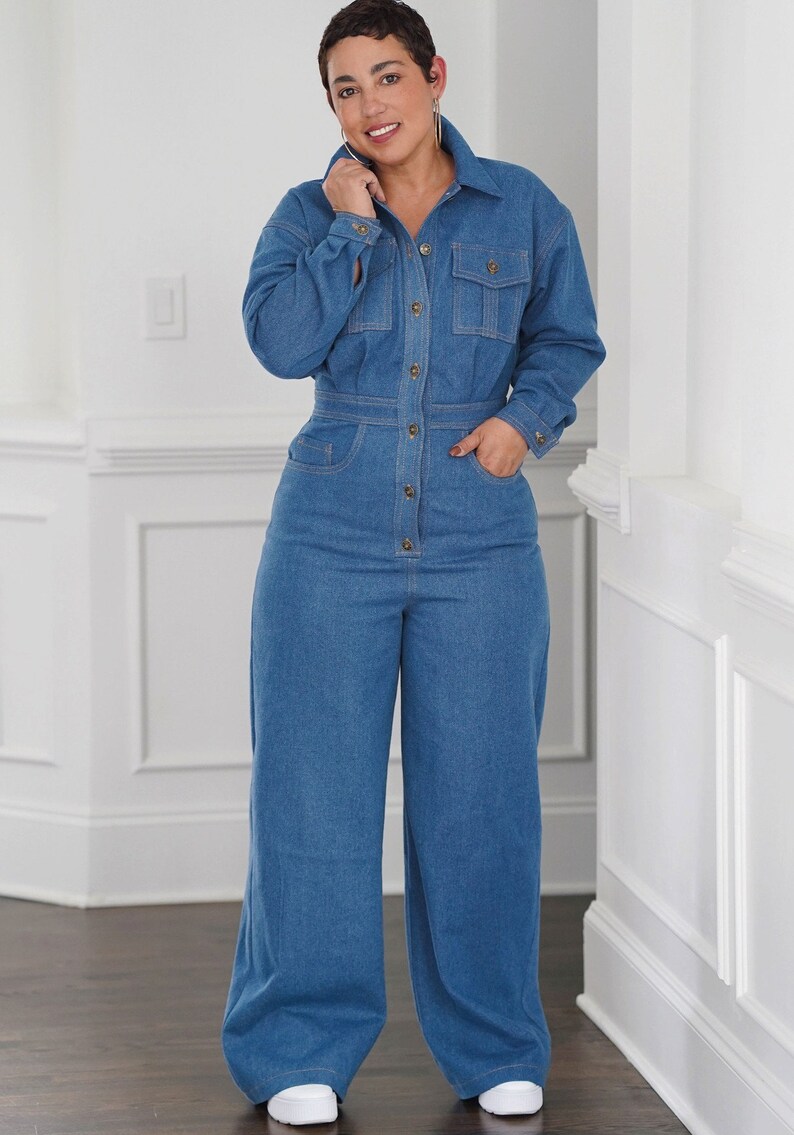 Peut inclure: Une femme portant une combinaison en jean bleu &agrave; manches longues et &agrave; fermeture boutonn&eacute;e. La combinaison a une taille cintr&eacute;e et des jambes larges.