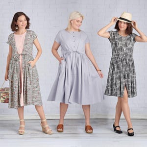 May include: Three women modeling dresses. The dresses include a striped dress with a pink underdress, a solid gray dress, and a black and white patterned dress. Each dress has a button-down front and pockets. The women are wearing sandals and heels.