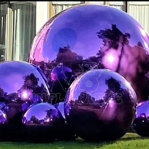 May include: A group of five large, reflective, purple spheres. The spheres are arranged in a cluster, with the largest sphere in the center.