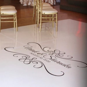 May include: White dance floor with a black and white custom design that says "[Name] & [Name] August 30, 2020".