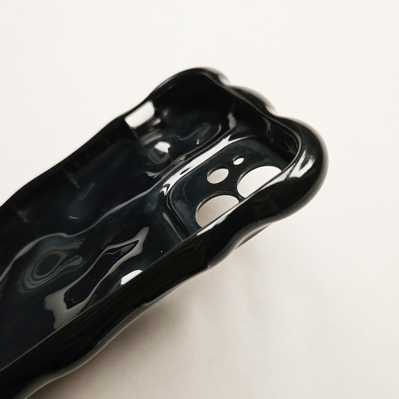 May include: Black phone case with a unique, abstract, liquid-like design. The case has a cutout for the camera lens.