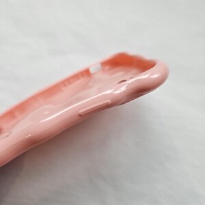 May include: A close-up of a pink silicone phone case. The case has a smooth, glossy finish and a slightly textured design.