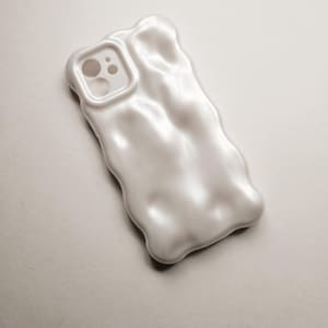 May include: A white phone case with a unique, textured, melted-looking design. The case has a cutout for the phone's camera.