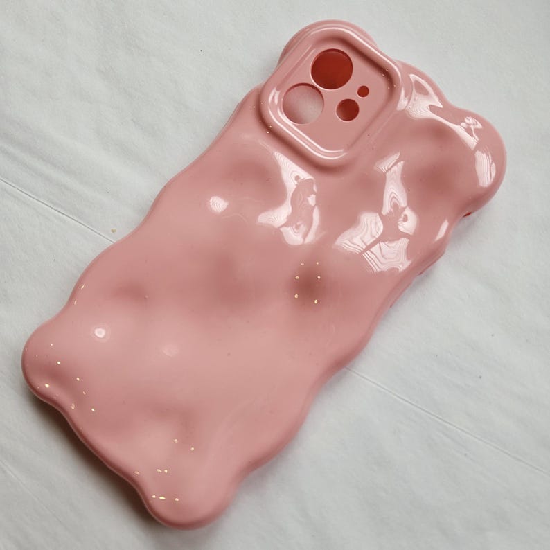 May include: A pink, gummy bear-shaped phone case with a cutout for the camera lens.