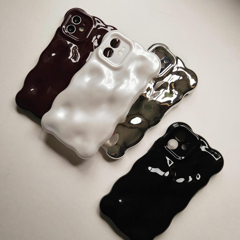 May include: Four phone cases in different colors and textures. The cases are made of a soft, flexible material and have a unique, abstract design. The cases are available in black, white, silver, and burgundy.